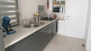 Una cucina moderna con lavello in acciaio inossidabile, macchina da caffè e forno a microonde sul piano di lavoro.