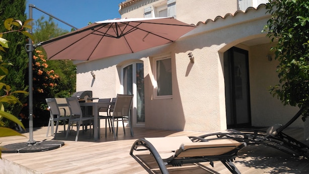 Un patio con tavolo e sedie, un barbecue e un ombrellone.