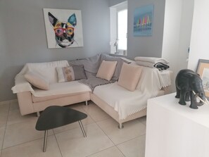 A modern living room with a beige sectional sofa, a black coffee table, and a black elephant sculpture on a white table.