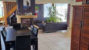 Un vaste espace de vie comprenant une table à manger, des canapés et un escalier.