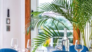 A dining table set with chairs, a potted plant, and a view of the outdoors. - Villa, heated pool, exceptional view, exotic garden, 4-star rating (Montbazin)