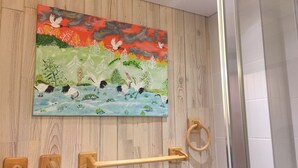 A wooden wall with a painting of birds and trees, a wooden towel bar, and a towel ring. - Apartment in the center of the village of Combloux (Combloux)