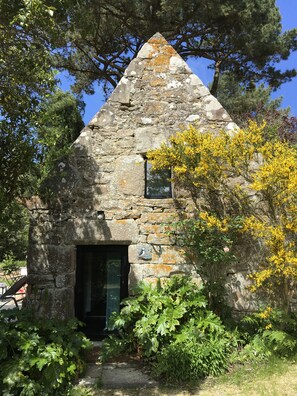 Ein Steinhaus mit einem dreieckigen Dach, einem kleinen Fenster und einer Tür.