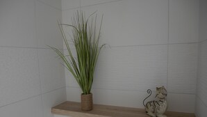 A bathroom with a wooden shelf holding a potted plant and a ceramic cat figurine. - Les balcons de Fellering: Spacious apartment with panoramic view (Fellering)