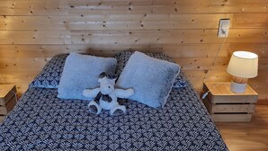 A bed with patterned bedding, two pillows, a stuffed toy, and bedside lamps on wooden nightstands. - Les balcons de Fellering: Spacious apartment with panoramic view (Fellering)