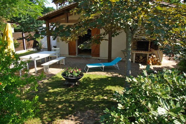 A patio area with a table and benches, a blue lounge chair, and a barbecue grill.