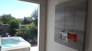 A room with a hot tub, a painting of boats, and a view of greenery outside. - Fully renovated house, all comforts, near beach, free wi-fi access.  (La Bernerie-En-Retz)