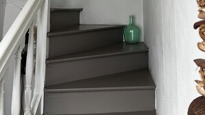 Een trap met een groene fles op de overloop, een visdecoratie aan de muur en een bordje met de tekst 