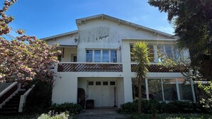 A two-story building with a white facade, a covered porch, and a clear blue sky.