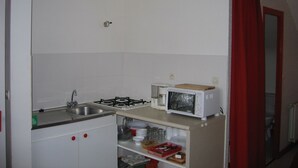 A small kitchen with white cabinets, a gas stove, a microwave, and a sink. - Countryside apartment near the sea (sleeps 2 to 4) (Erquy)