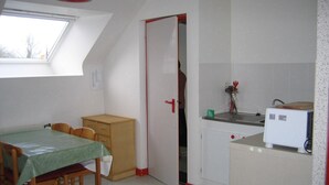A compact kitchen with a dining area, a small refrigerator, and a window with a view. - Countryside apartment near the sea (sleeps 2 to 4) (Erquy)