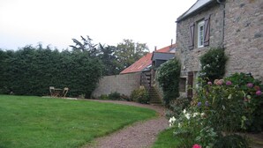 A stone building with a gravel path leading to a wooden deck. - Countryside apartment near the sea (sleeps 2 to 4) (Erquy)