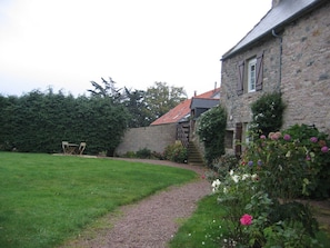 Un bâtiment en pierre avec un chemin de gravier menant à une terrasse en bois.