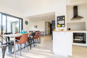 A modern kitchen with a built-in oven and a dining area with a table and chairs.