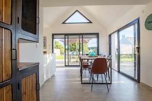 A spacious dining area with a high ceiling, large windows, and a view of the outdoors.