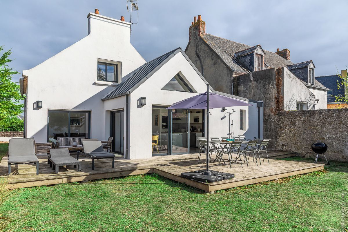 A modern house with a patio area, outdoor furniture, and a barbecue.