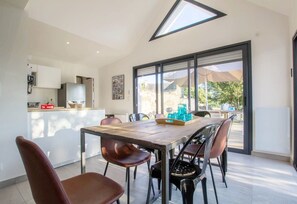 A modern kitchen with a dining area, large windows, and a view of the outdoors.