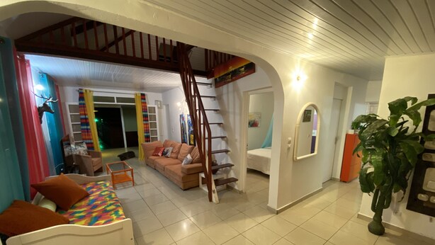 A spacious living area with a staircase, a sofa, a bed, and a staircase leading to an upper level. - Luxury karukera villa in st-francois with private pool tel0690071415 (saint-francois)