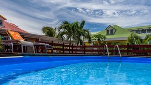 A swimming pool with clear blue water, a wooden fence, and palm trees in the background. - Luxury karukera villa in st-francois with private pool tel0690071415 (saint-francois)