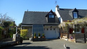 A two-story house with a garage, a sloped roof, and a small garden area with potted plants. - Relaxing holiday / wifi (Concarneau)