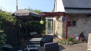 An outdoor patio with wicker furniture, a striped tablecloth, and a large umbrella. - Relaxing holiday / wifi (Concarneau)