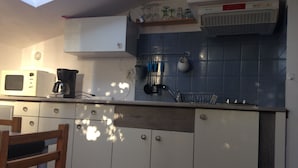 A kitchen with a microwave, coffee maker, and a sink. There is a shelf above the sink with glassware. - Relaxing holiday / wifi (Concarneau)