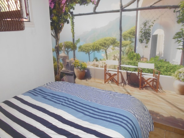 Una habitación con cama, vistas a un jardín y una mesa con sillas.
