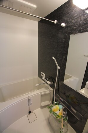 Un baño moderno con bañera, ducha y un espejo grande.