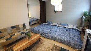 Un dormitorio con una cama grande, un sofá, una mesa de centro de madera y una televisión.