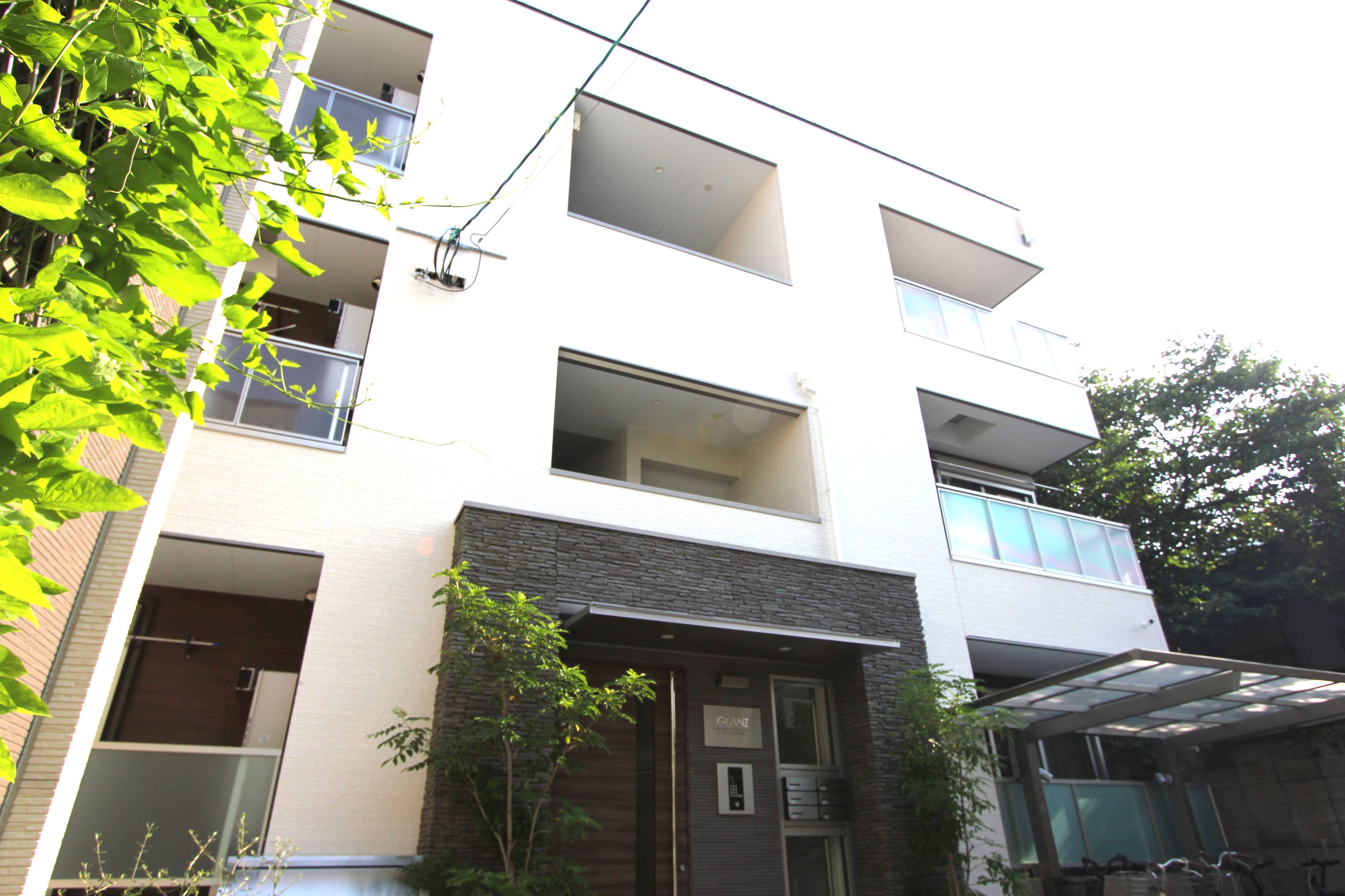 A modern multi-story building with balconies, a garage, and a small garden area.