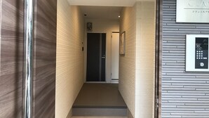 Un pasillo moderno con una puerta al final, una cámara de seguridad y un panel de control instalado en la pared.