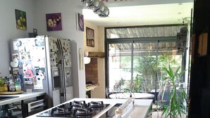 Een keuken met een centraal eiland, een koelkast en een eethoek met een tafel en stoelen.
