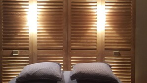 Een slaapkamer met een bed, twee kussens en houten louvre-kasten met verlichting.