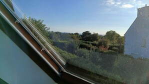 A view from a window overlooking a garden with a white building and trees. - Seaside house in South Finistère, 300m from the beach. (Combrit)