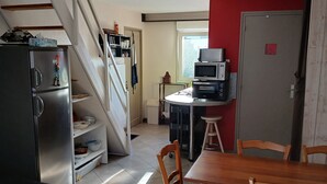 A kitchen with a dining area, a refrigerator, a microwave, and a staircase. - Seaside house in South Finistère, 300m from the beach. (Combrit)