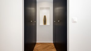Un pasillo con puertas de madera oscura, una pared blanca y suelo de madera.