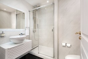 Une salle de bain moderne avec une douche à parois de verre, un lavabo blanc et des toilettes.
