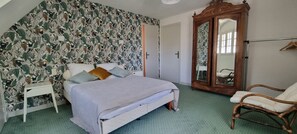 Un dormitorio con cama, mesita de noche, armario y una silla.
