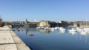 Un puerto con barcos amarrados, un muro de piedra y cielo despejado.