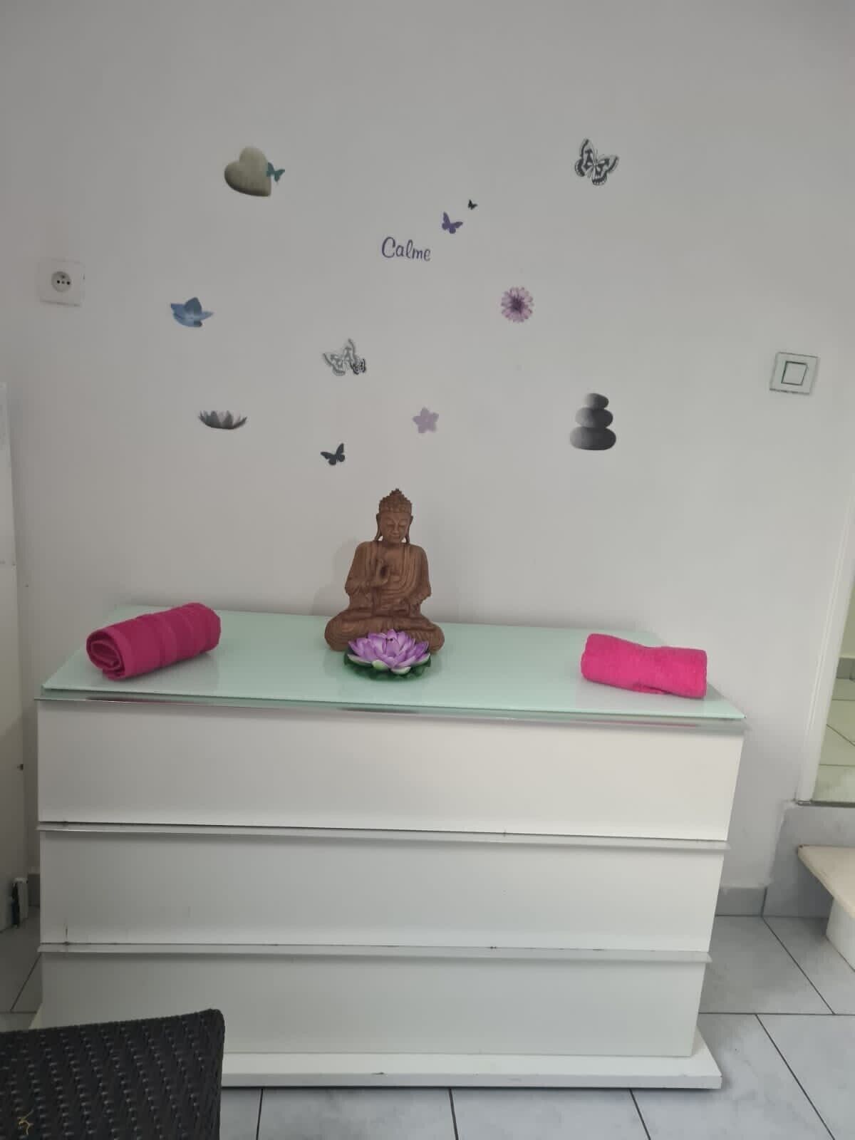 Un espace dédié à la méditation, agrémenté d’une statue, d’une fleur de lotus et d’autocollants décoratifs sur les murs.