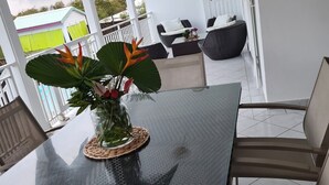 Un espacio moderno para comer al aire libre con mesa de vidrio, sillas de mimbre y una planta en maceta.