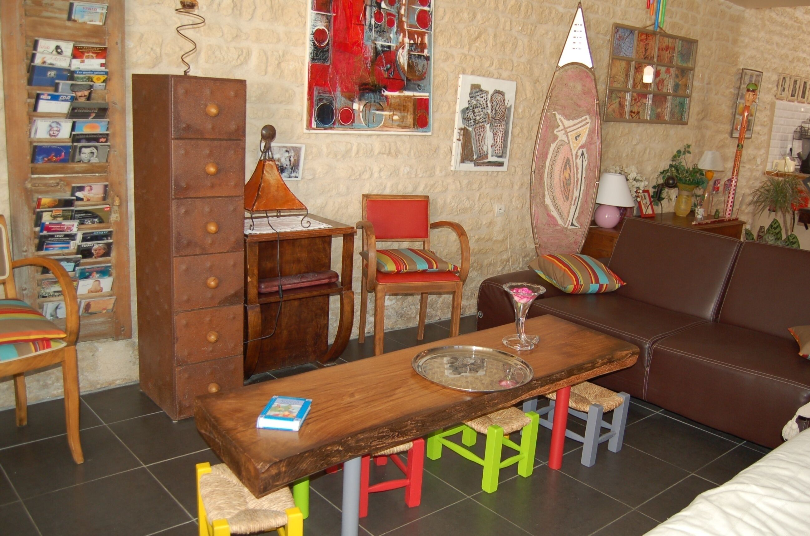 Een gezellige woonkamer met een houten salontafel, een rode stoel, een bruine bank en een boekenplank vol boeken en tijdschriften.