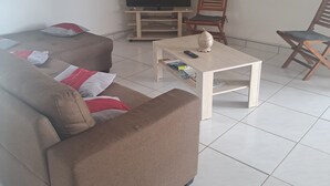 A living room with a brown sofa, a coffee table, a television, and wooden chairs. - HAUT DE VILLA VIEUX FORT (VIEUX FORT)