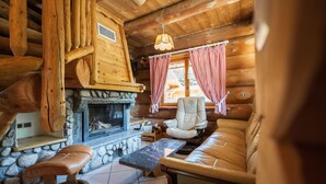 A cozy cabin interior with a stone fireplace, a leather sofa, a wooden bench, and checkered curtains. - La fuste des Chevaux, log cabin, kota-sauna, Nordic bath, 6 people (La Bresse)