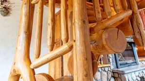 A wooden spiral staircase with a stone fireplace at the bottom. - La fuste des Chevaux, log cabin, kota-sauna, Nordic bath, 6 people (La Bresse)