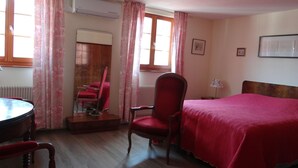 Een hotelkamer met een bed, een stoel, een tafel en een radiator.