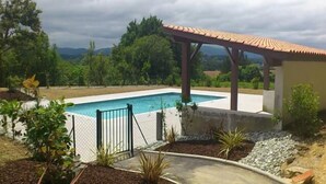 A swimming pool with a pergola and a view of the surrounding landscape.