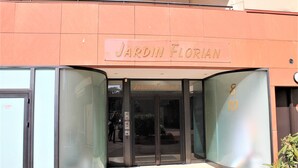La entrada a Jardin Florian, con un puerta de cristal y un letrero arriba.