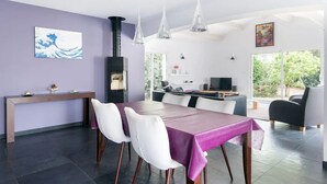 Ein moderner Essbereich mit einer violetten Tischdecke, weißen Stühlen und Pendelleuchten.