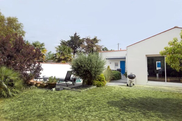 A modern house with a white exterior, a blue door, and a well-maintained lawn.